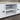 White wooden cabinet with black knobs on a gray floor.