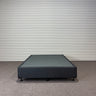 Charcoal fabric, bed base, made in New Zealand, pine wood, corner guard protection, on a gray floor with a striped wall background