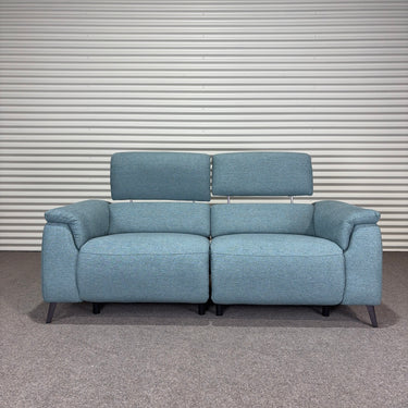 Blue power sofa with black metal legs, against a striped wall