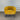Yellow armchair with black legs against a corrugated metal wall.