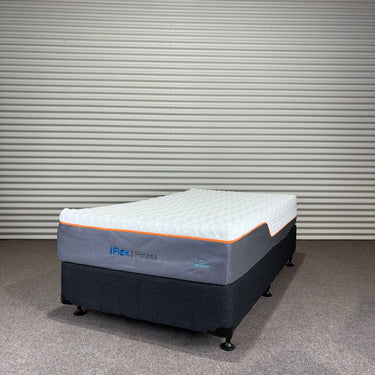 Mattress with 'iFlex 3 Fitness' branding on a gray floor against a corrugated metal wall.