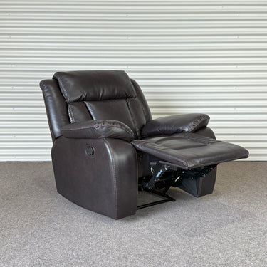 Black leather look recliner chair on a gray floor with a white wall background