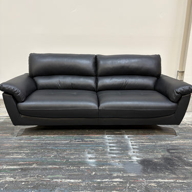 Black leather sofa on a gray floor with a neutral wall background