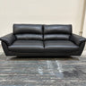 Black leather sofa on a gray floor with a neutral wall background