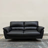 Black leather sofa on a wooden floor with a plain wall background