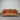 Brown sofa with wooden frame against a corrugated metal wall.