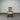 Wooden rocking chair with a white cushion against a corrugated metal wall.