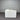 White cube-shaped ottoman on a gray floor with a ribbed gray wall in the background