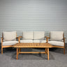 Outdoor furniture set with wooden table and beige cushions against a corrugated metal wall.