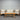 Outdoor furniture set with wooden table and beige cushions against a corrugated metal wall.