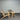 Two wicker chairs and a small round table against a corrugated metal wall.
