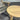 Wooden round table on a gray surface with a wicker chair in the background
