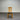 Wooden chair with a black seat against a corrugated metal wall.