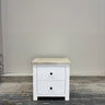 White nightstand with a wooden top against a gray wall.