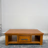Wooden coffee table with a drawer on a gray floor against a white wall