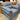 Gray upholstered sofa with brown armrests in a showroom setting