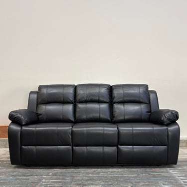Black leather sofa on a wooden floor with a neutral wall background