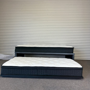 Two mattresses on a gray floor with a corrugated metal wall background