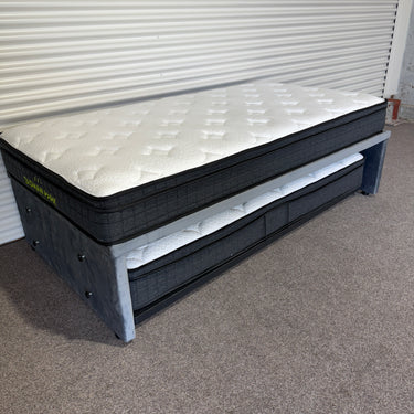 Gray mattress with storage drawers on a carpeted floor against a white wall.