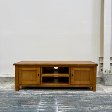 Wooden TV stand in a room with a light gray floor and white walls.