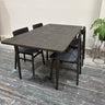 Dark wooden dining table with four chairs in a room with a plant.