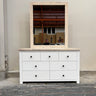 White dresser with a mirror on top in a warehouse setting