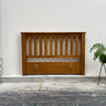 Wooden headboard against a white wall with a plant on the right side.
