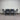 Outdoor furniture set with a table and four chairs against a corrugated metal wall.