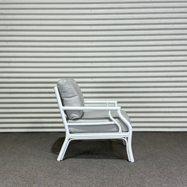 White chair with gray cushion against a corrugated metal wall.