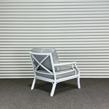 White chair with gray cushions against a corrugated metal wall.