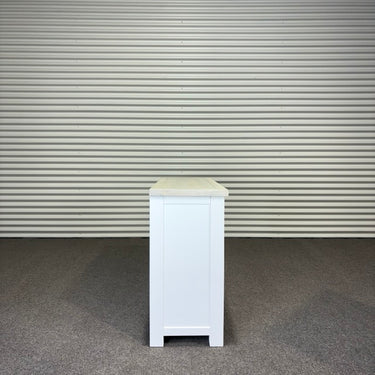 White cabinet with beige top against a corrugated metal wall.
