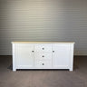 White sideboard with wooden top against a corrugated metal wall. Kinloch collection