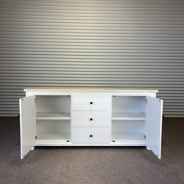 White cabinet with open doors against a corrugated metal wall. kinloch collection