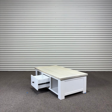 White coffee table with a drawer against a corrugated metal wall.