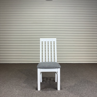 White chair with a gray cushion against a corrugated metal wall. Kinloch collection