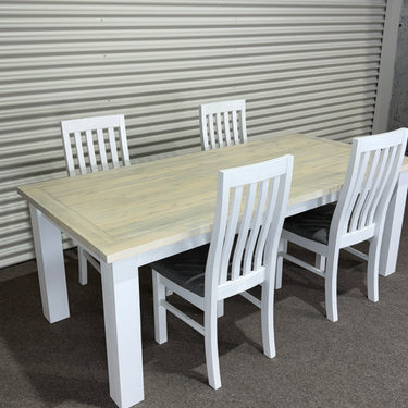 Dining table set with four chairs against a corrugated metal wall. kinloch collection