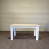 Wooden table with white base against a corrugated metal wall.