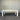 White table with a light wood top against a corrugated metal wall.