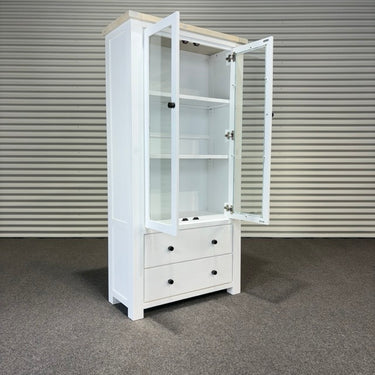 White cabinet with glass doors and drawers against a striped wall.