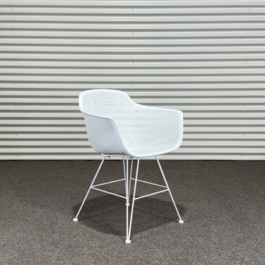 White chair on a gray carpet with a corrugated metal wall in the background