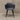 Dark gray chair with black legs against a beige wall.