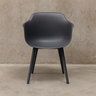 Dark gray chair with black legs against a beige wall.
