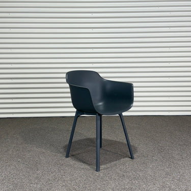 Black chair against a corrugated metal wall.