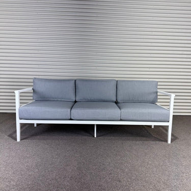 Gray sofa with white frame against a corrugated metal wall.