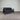 Black sofa with cushions against a corrugated metal wall.