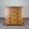 oat Wooden dresser with four drawers against a corrugated metal background