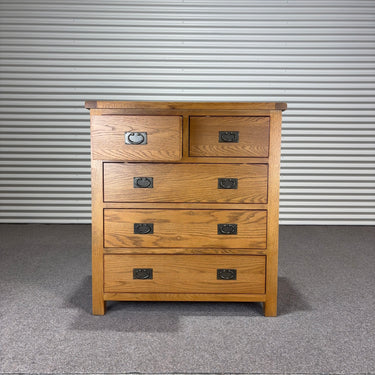 Wooden dresser with four drawers against a corrugated metal wall.