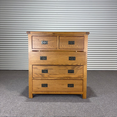 Wooden dresser with four drawers against a corrugated metal wall.