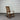 Wooden rocking chair with a white cushion against a corrugated metal wall.