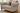 Beige sofa with decorative pillows on a wooden floor in a room with a dresser.